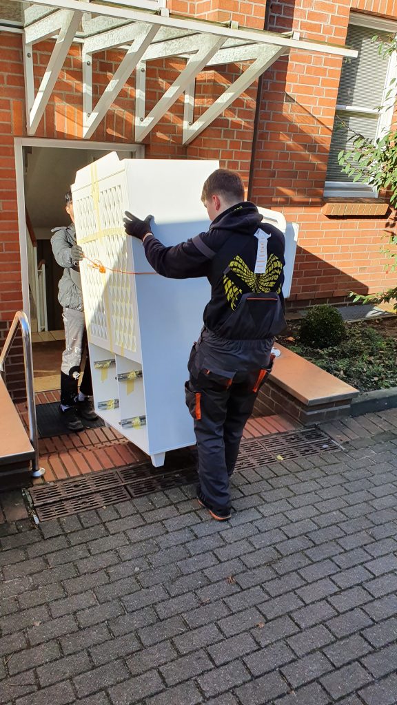 Tragehelfer tragen einen Schrank aus einem Haus hinaus